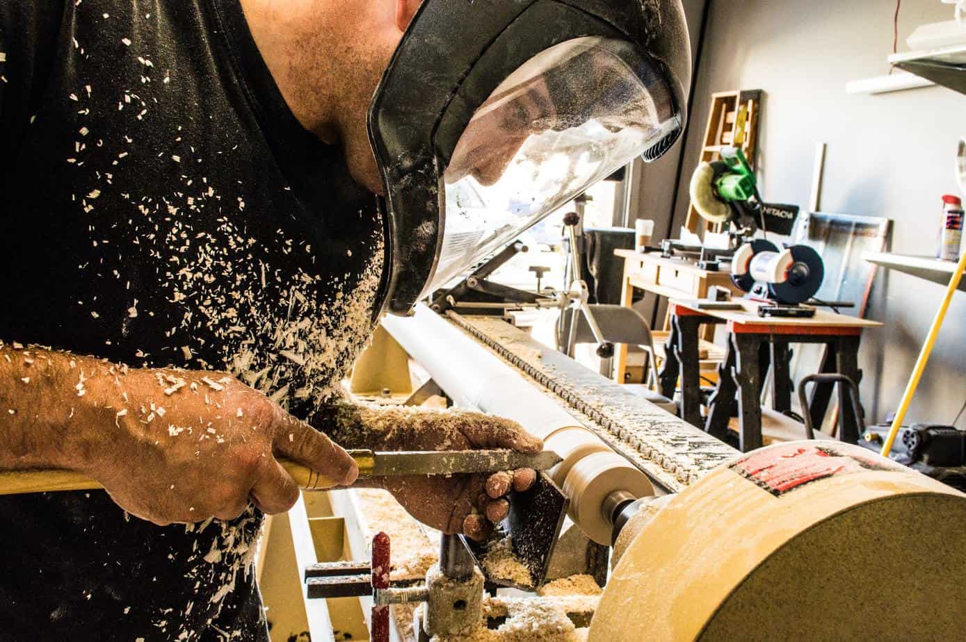 photo of a man carving wood on a turning spindle.