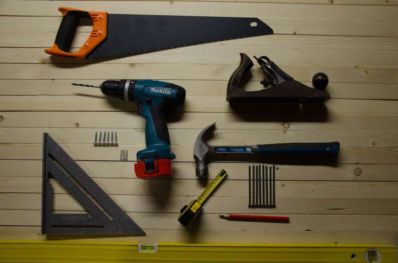 photo of a saw, drill, plane, hammer and other tools on a wall.