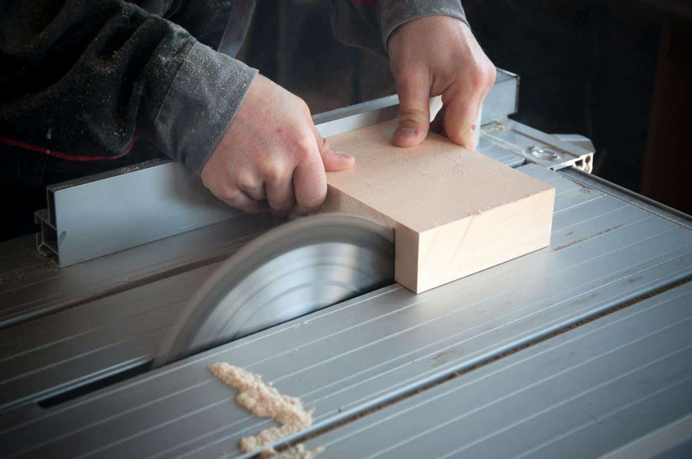 photo of a man using a table saw to cut wood.
