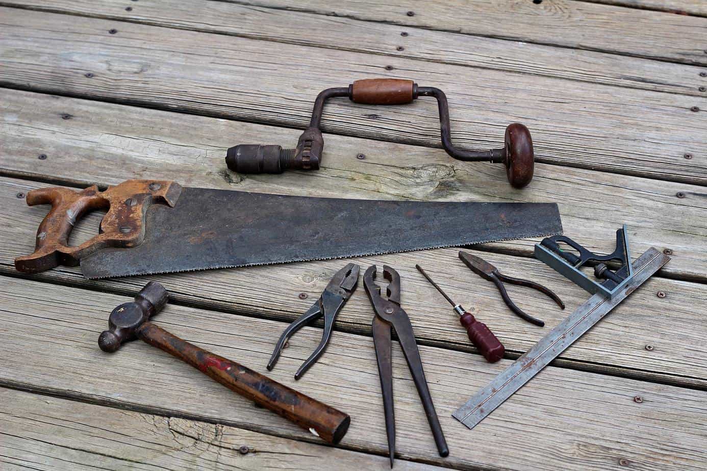 photo of old rusted woodworking tools on a worn wooden deck.