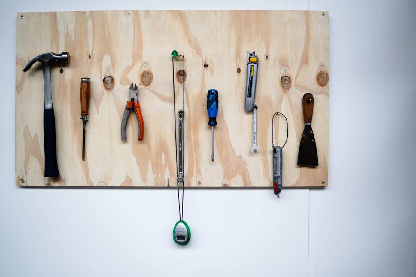 photo of a piece of plywood used as a wall mounted tool storage area with a couple of extremely clean tools on it.