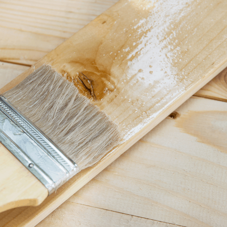 photo of a paint brush applying shellac to a board of wood.