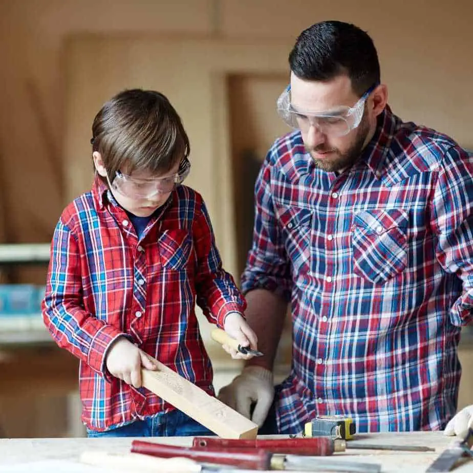 photo of a man showing a boy how to carve wood