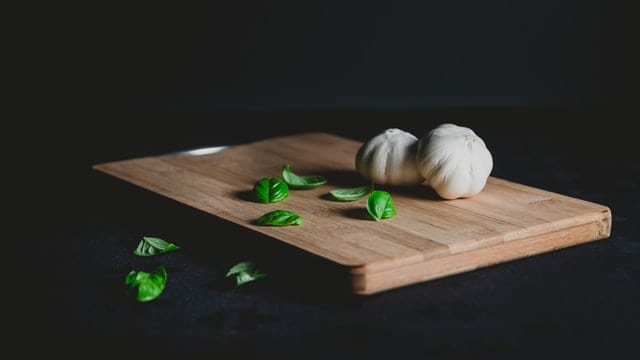 photo of a cutting board with garlic and basil on the top.