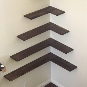 Photo of floating shelves make out of black walnut on the corner of a living room