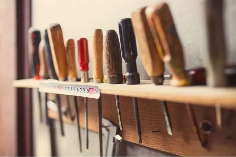 photo of an assortment of tools on a wall mounted rack.